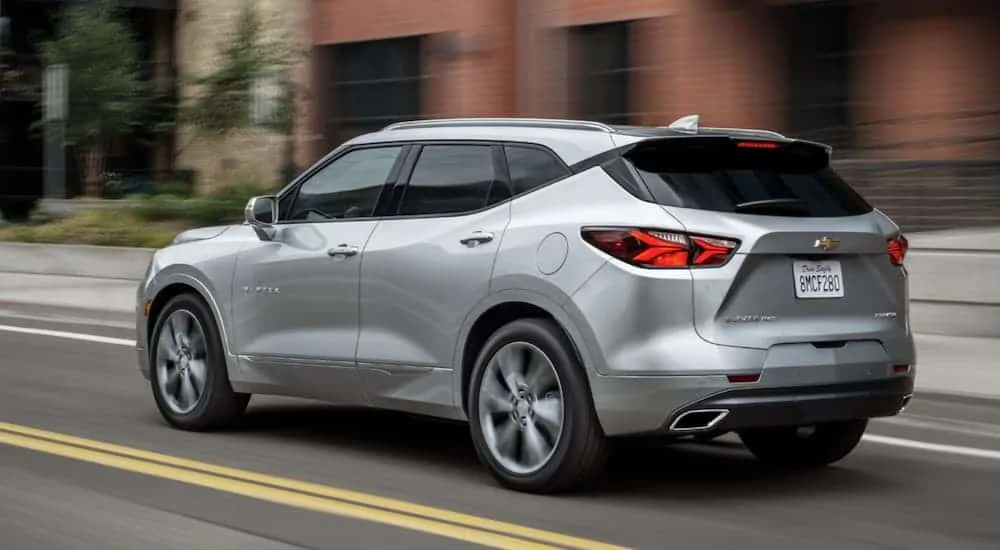 A silver 2020 Chevy Blazer is driving past brick buildings.