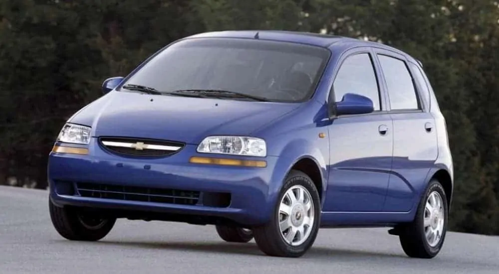 A blue 2004 Chevy Aveo is parked in an empty parking lot. 