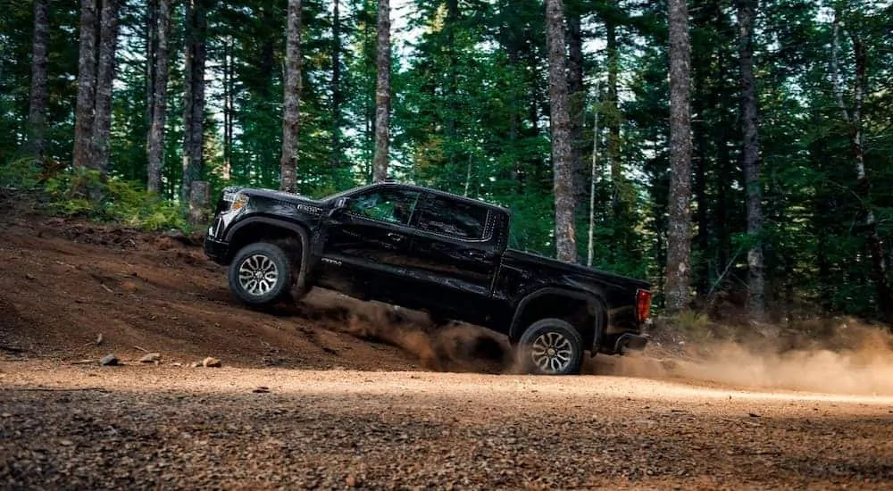 A black 2020 GMC Sierra 1500 is off-roading in the woods.