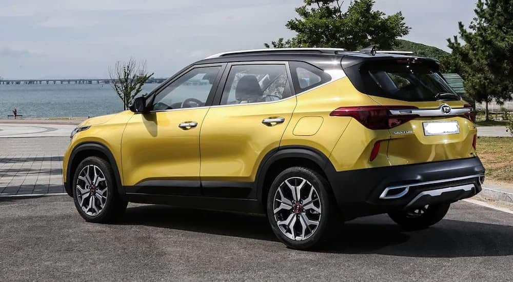 A yellow 2020 Kia Seltos is parked in a parking lot next to a body of water. 
