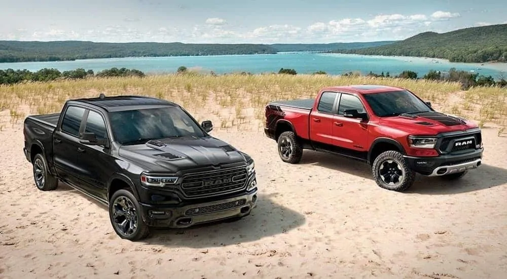Two special edition 2020 Ram 1500s, which win when comparing the 2020 Ram 1500 vs 2019 Ram 1500, are parked at the beach.
