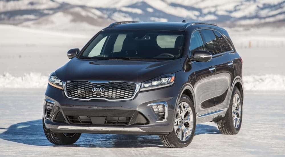 A grey 2020 Kia Sorento, which is a popular Kia SUV, is parked on snowy flat land with mountains in the distance.