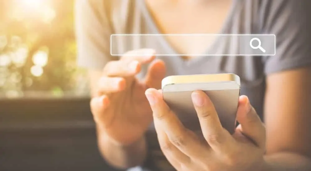 A woman is on her phone and a search bar is displaying above it.