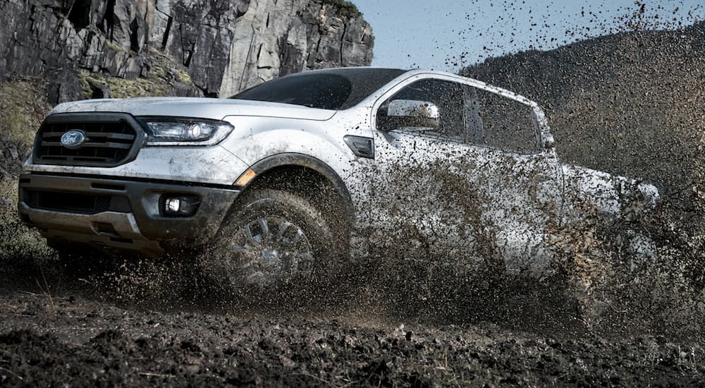 Mud is spraying into the air while a silver 2020 Ford Ranger drives through a mud pit.