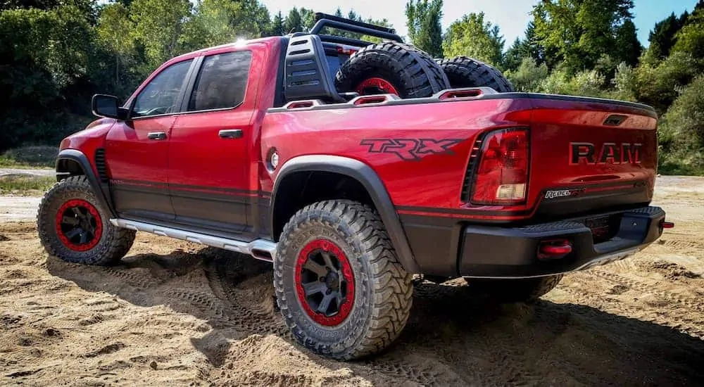 A dark red Ram TRX, which is soon to be a new model among Ram trucks, is parked in a dirt lot with an off-road set up.