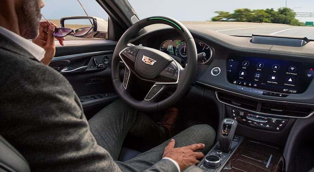 A man is sitting in the front seat on the black leather interior of a 2020 Cadillac CT6.