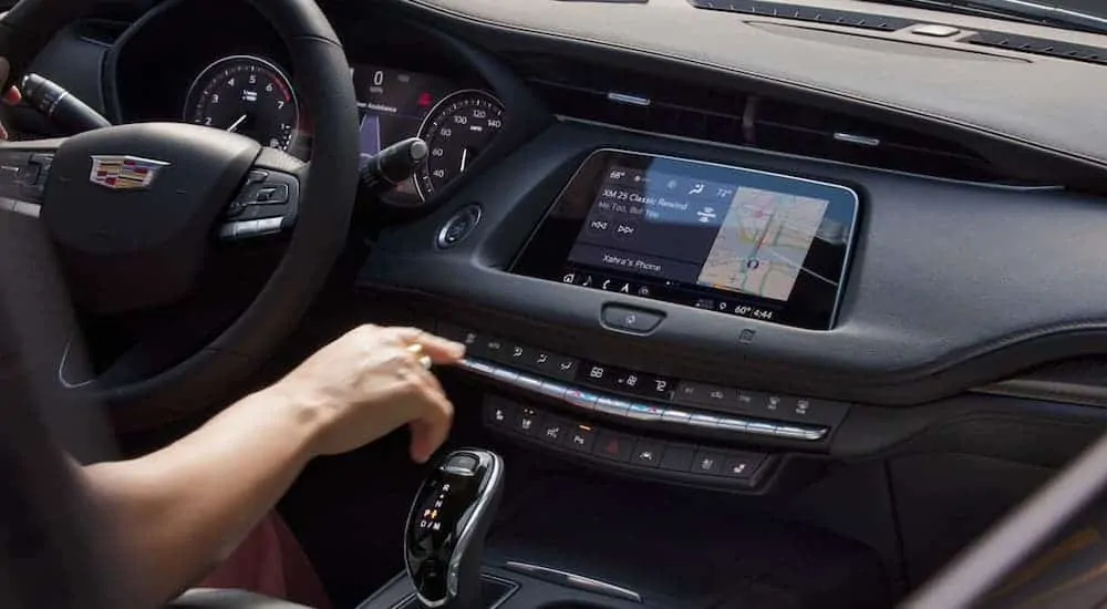 The front black leather interior of the 2020 Cadillac XT4 is shown with an infotainment system. 
