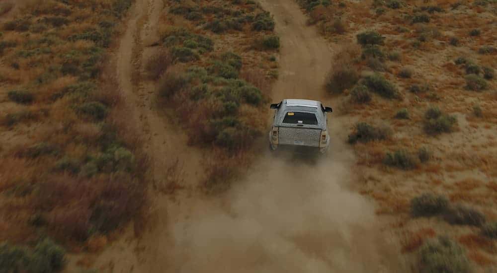 A spy shot of the 2020 Ford Bronco shows it driving on a dirt trail.