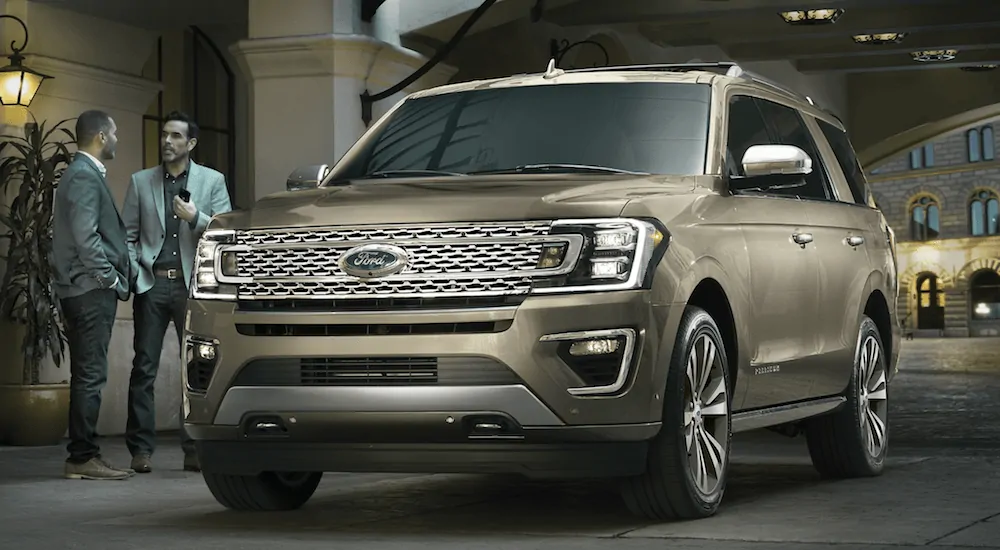 Two men are talking while standing next to a gold 2020 Ford Expedition, which is a popular option among Ford SUVs. 