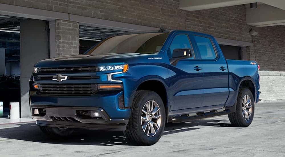 A blue 2020 Chevy Silverado is parked in front of an open garage door. 