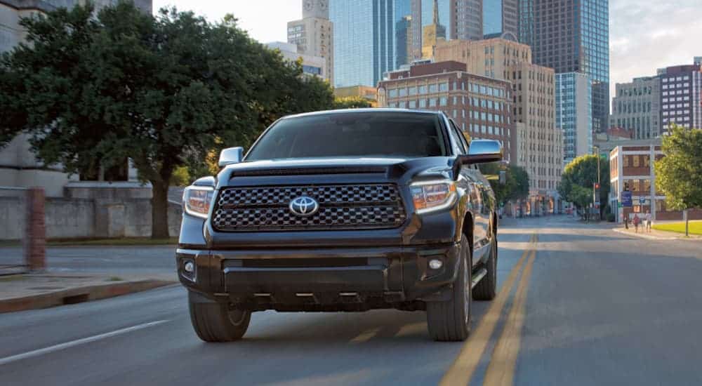 A black 2020 Toyota Tundra is facing forward while driving on a city street.
