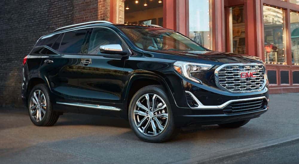 A blue GMC Terrain is parked in front of a store front.