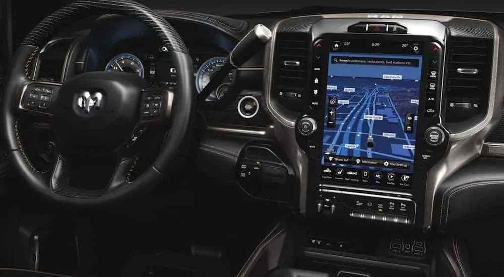 The front black leather interior of a 2020 Ram 2500 is shown with a 12-inch infotinament UConnect system. 