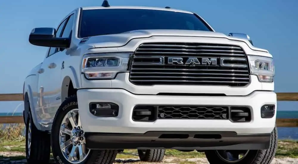 A white 2020 Ram 2500 is parked in a parking lot with an ocean in the distance. 