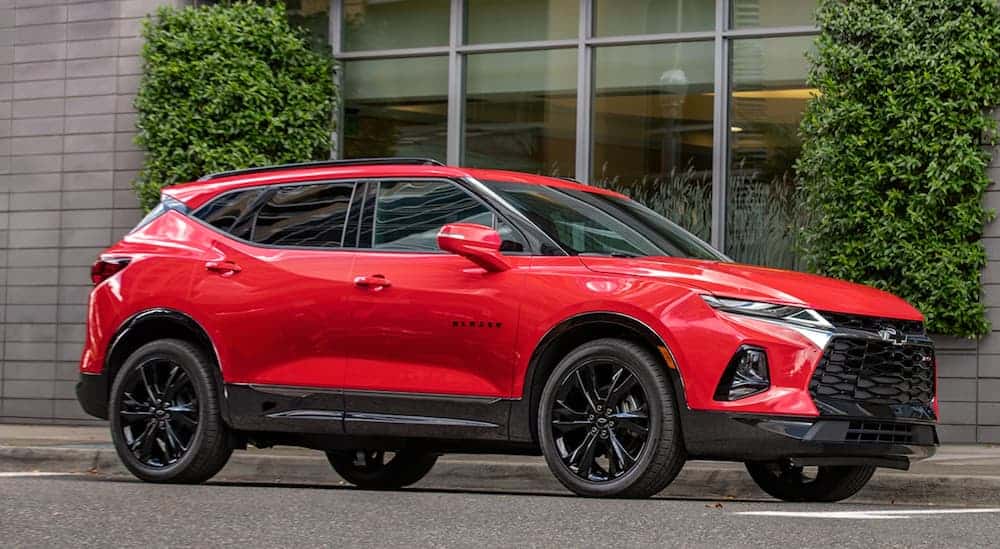 A red 2020 Chevy Blazer RS is parked in front of an office building with large windows. 