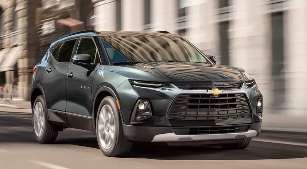 A dark green 2020 Chevy Blazer is driving on city street.