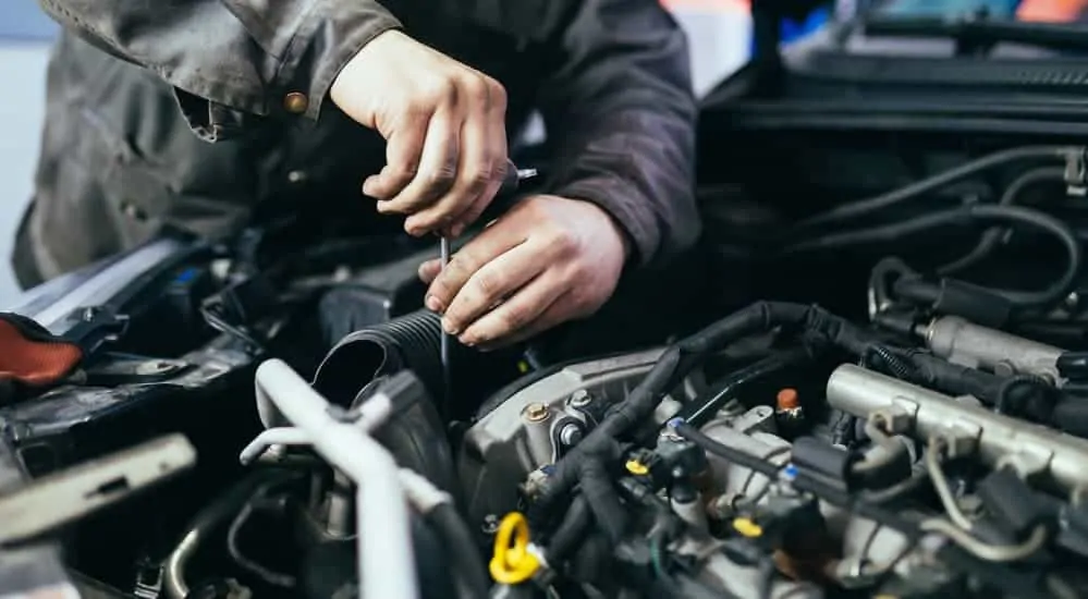 A licensed Cadillac mechanic is working in the engine bay of a pre owned Cadillac. 