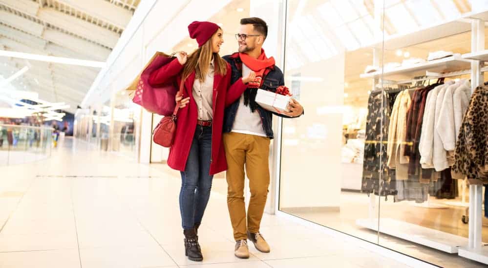 A millennial couple is walking through a mall shopping after looking at used car lots.