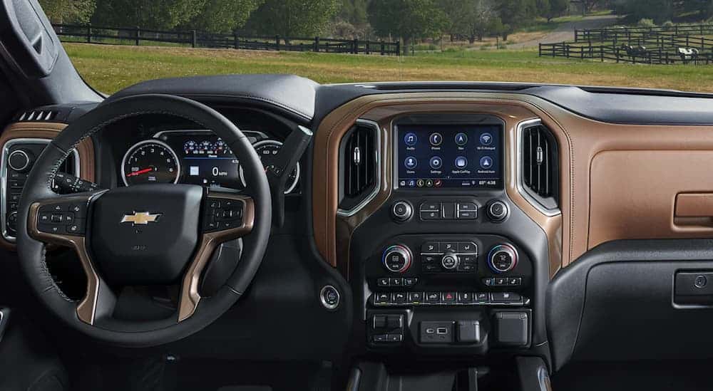 The front black and brown leather interior of a 2020 Silverado 1500 is shown with an infotainment system. 