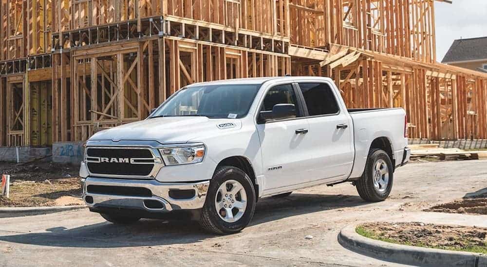 A white 2020 Ram 1500 is parked next to an unfinished home. 