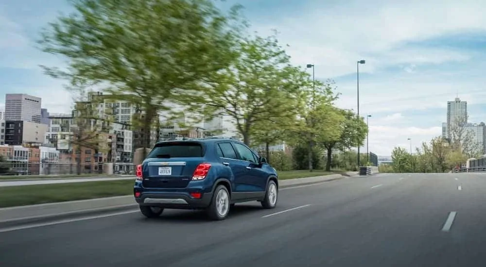 A blue 2020 Chevy Trax is driving towards a city.