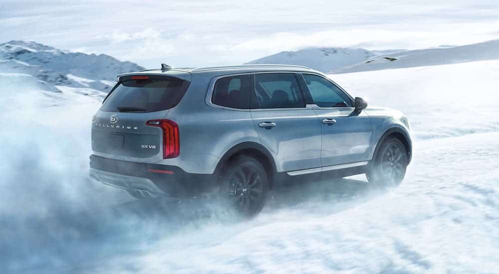 A light blue 2020 Kia Telluride is driving in the snow.