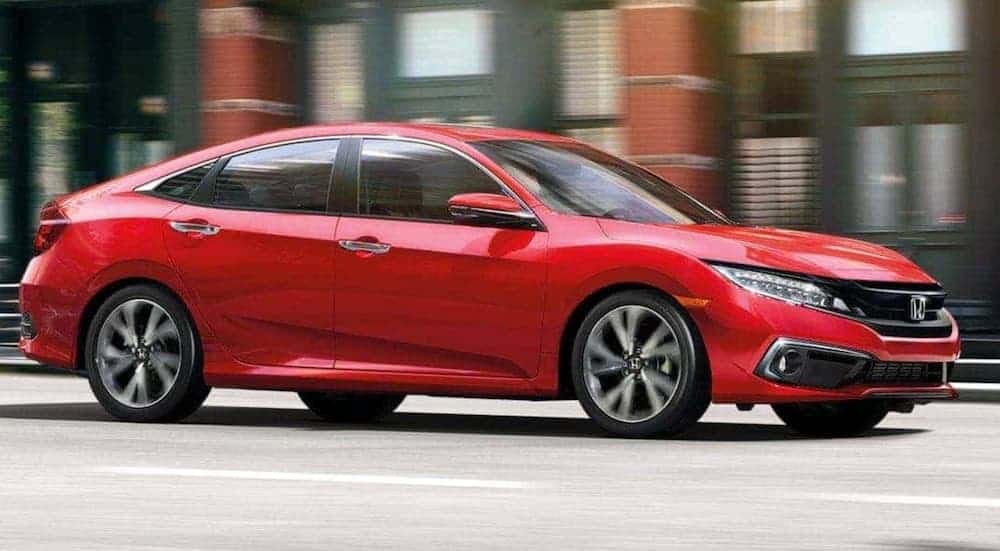 A red 2020 Honda Civic Sedan Touring is driving downtown.
