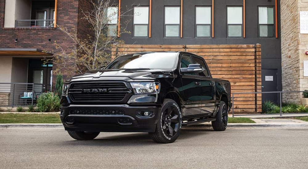 A black 2020 Ram 1500 is parked outside a modern house.