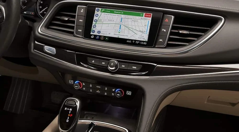 A close up of the front grey and tan interior of the 2020 Buick Enclave is shown with an infotainment system. 