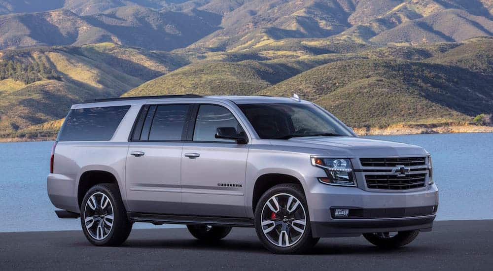 A grey 2020 Chevy Suburban is parked with mountains in the distance. 