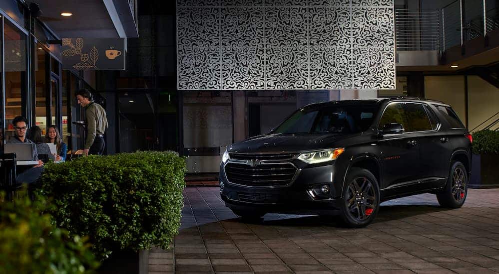 A black 2020 Chevy Traverse is parked in front of a restaurant at night. 