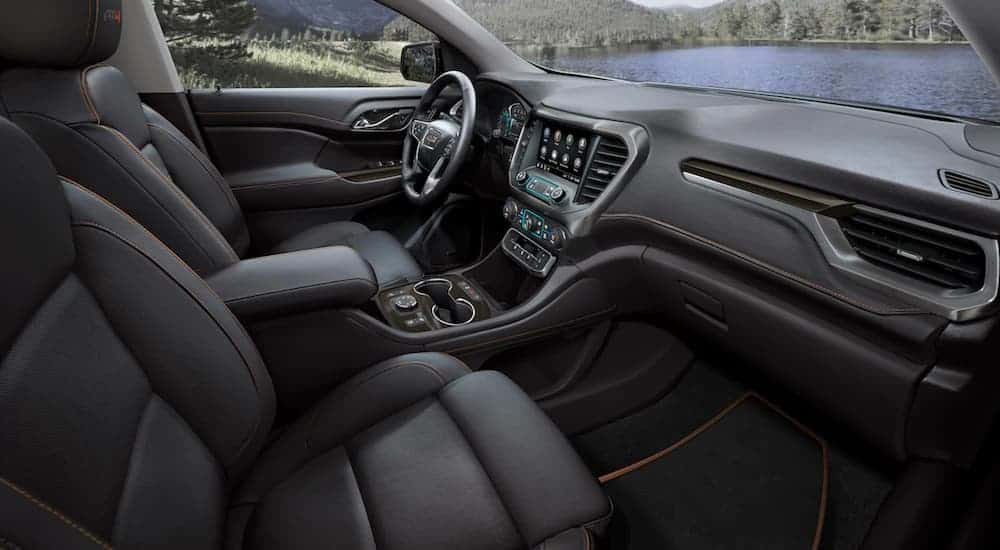 The front black leather interior of a 2020 GMC Acadia AT4 is shown with an infotainment system. 