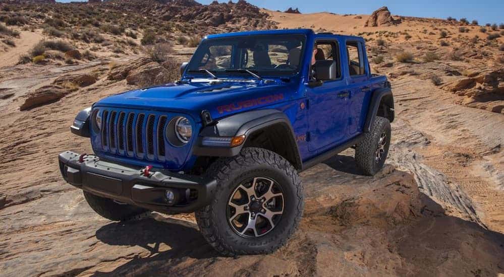 A blue 2020 Jeep Wrangler diesel is off-roading on a rocky terrain. 