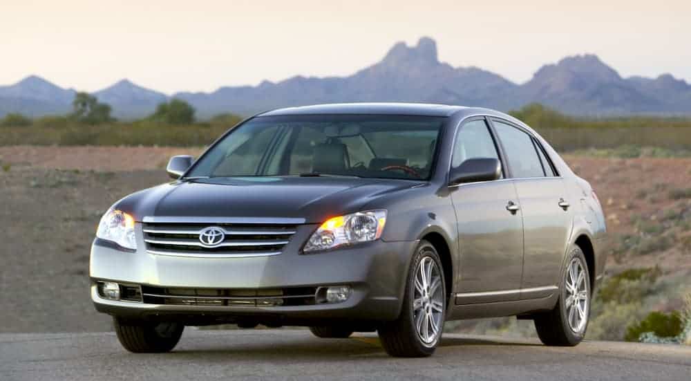 A grey 2007 Toyota Avalon is parked in front of desert mountains.