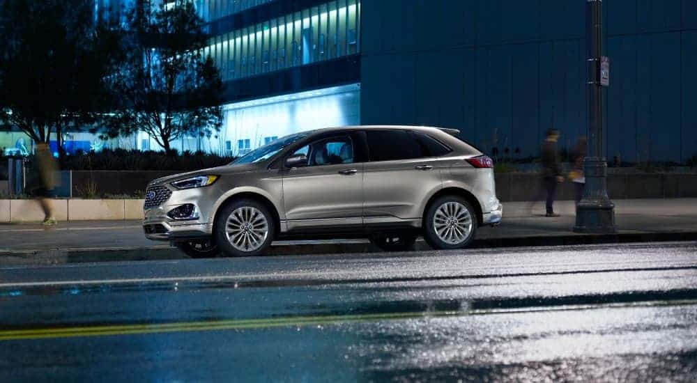 A silver 2020 Ford Edge is parked on a city street at night.