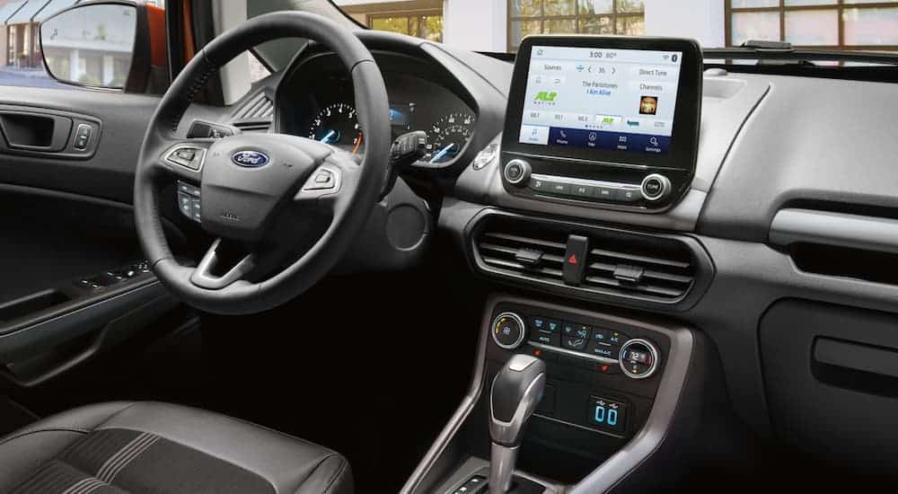 The front black leather interior of a 2020 Ford Ecosport is shown with an infotainment system. 
