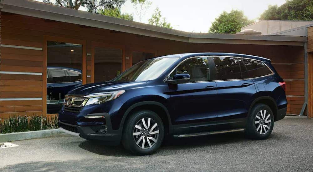A blue 2020 Honda Pilot is parked outside of a modern home.