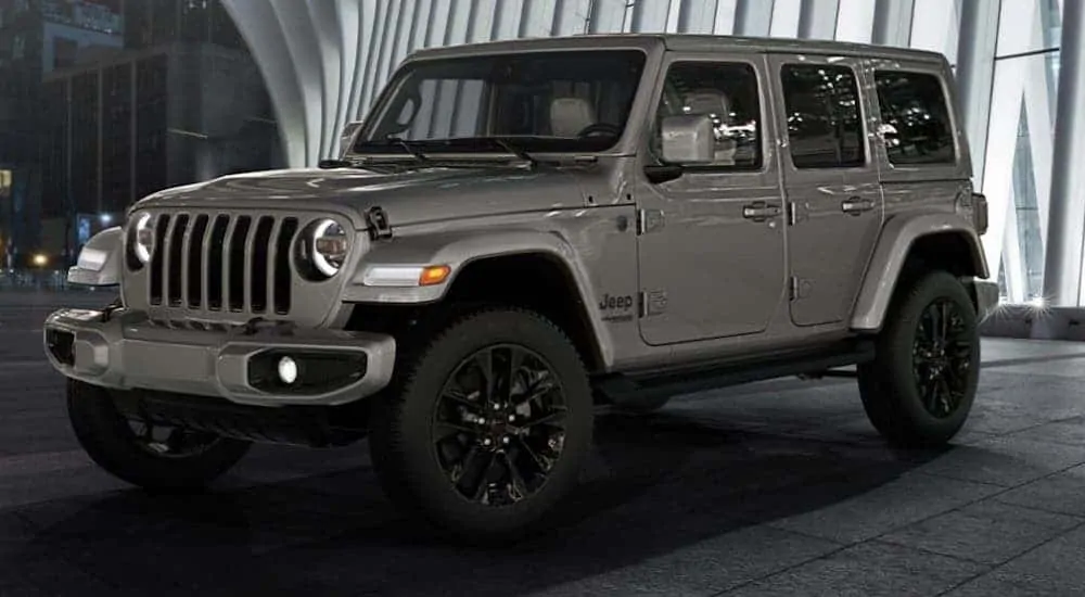 A dark gray 2020 Jeep Wrangler High Altitude edition is parked in front of a glass building.
