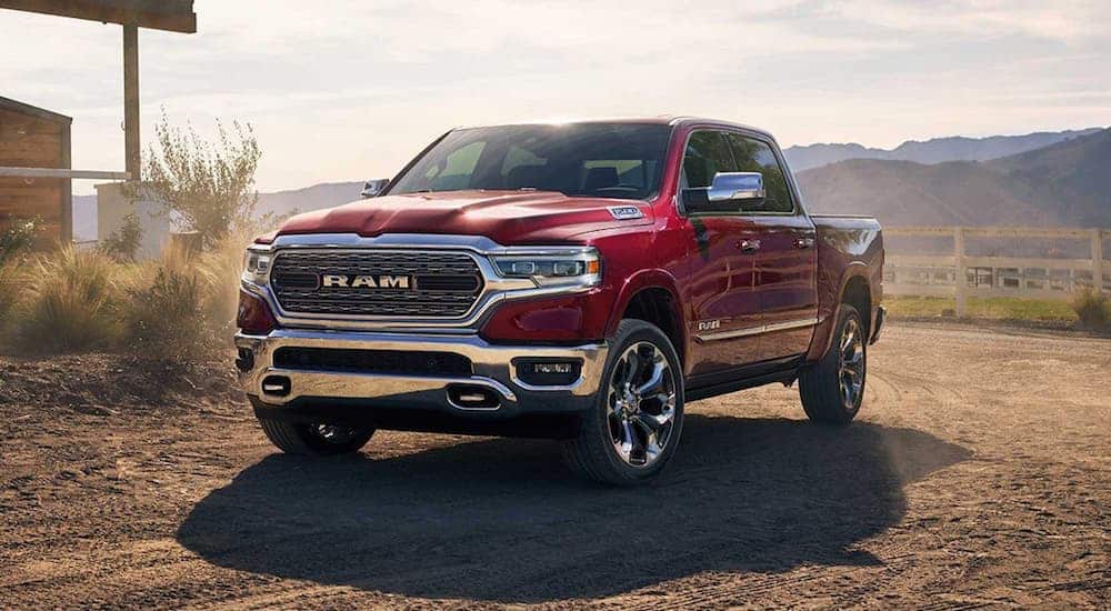 A red 2020 Ram 1500 is parked next to a home next with mountains in the distance.