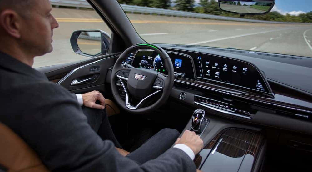 A man is sitting in the driver seat of a 2021 Cadillac Escalade while using the Super Cruise system.
