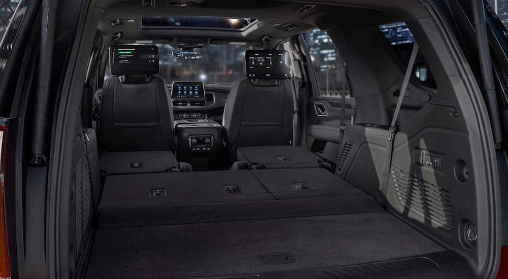 A look from the rear to the front of the black interior of a 2021 Chevy Tahoe is shown.