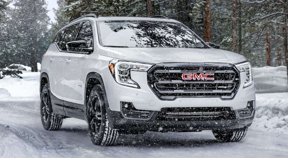 A white 2021 GMC Terrain AT4 is driving in the snow.