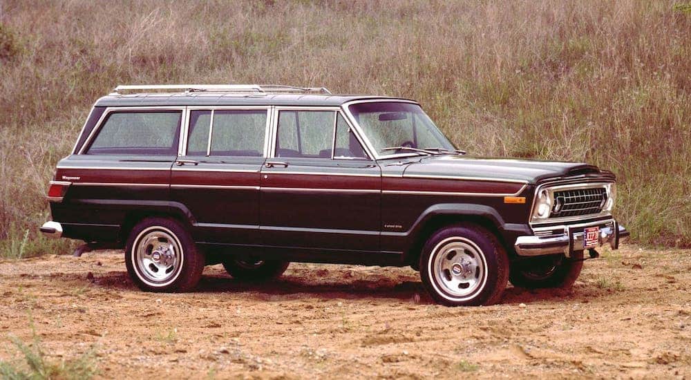 A black and wood 1978 Jeep Wagoneer is parked in a field.