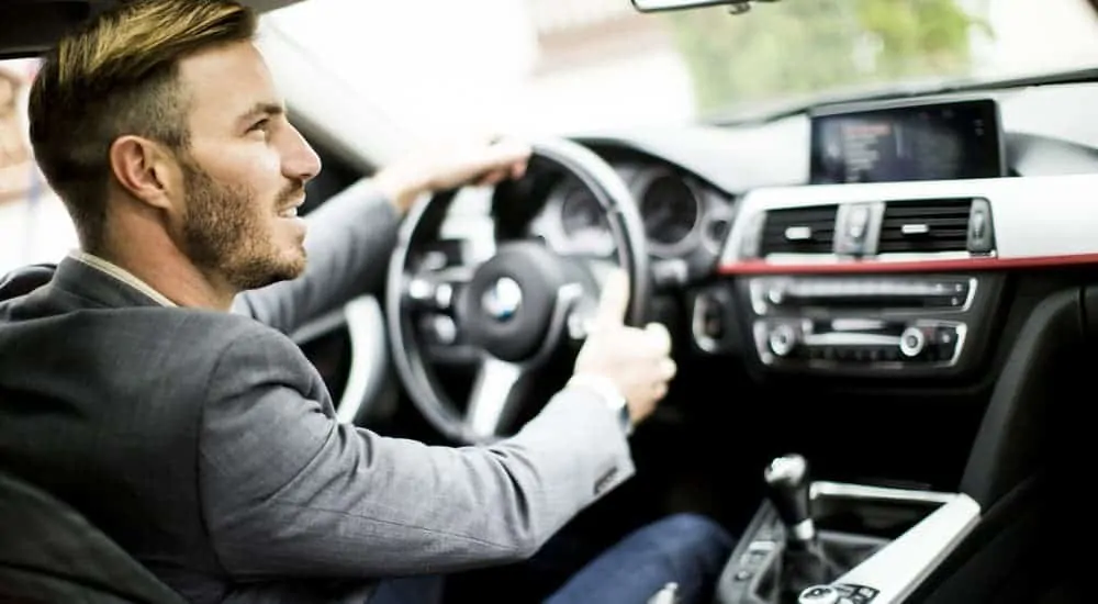 A man is driving a used car, shown from the inside.