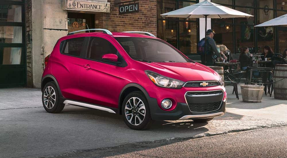 A pink 2020 Chevy Spark is parked in front of a cafe.