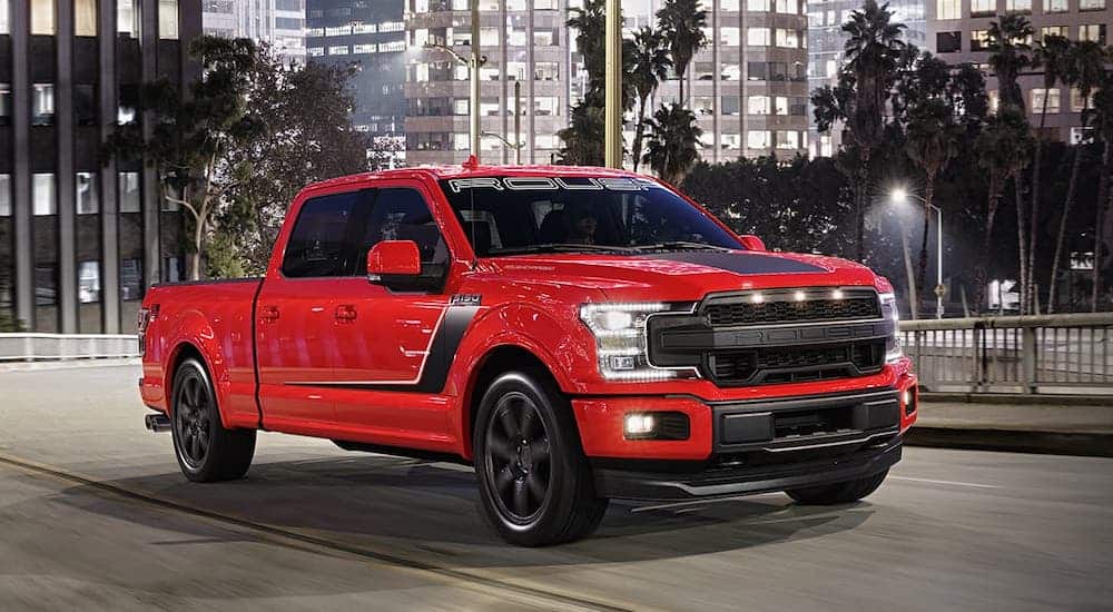 A red 2020 Ford F-150 Roush Nitemare is driving on a city street at night.