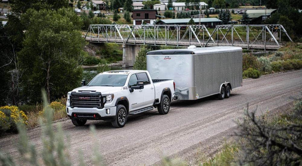 A white 2020 GMC Sierra HD AT4 from your local GMC dealer is towing a trailer.