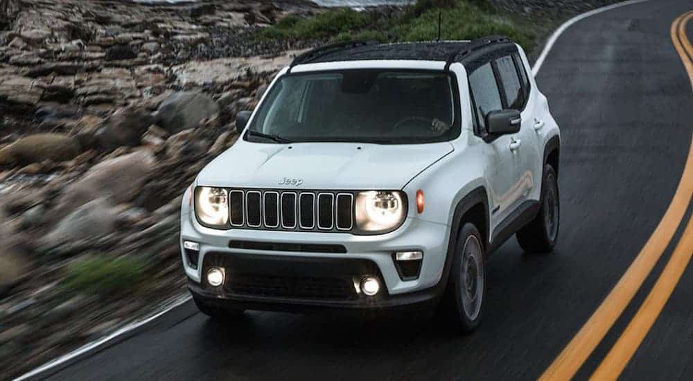 A white 2020 Jeep Renegade is driving past rocks.