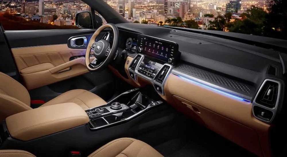 The luxurious tan and black front seat of a 2021 Kia Sorento is shown overlooking a city at night.