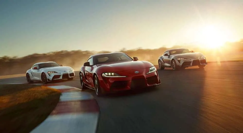 Three 2020 Toyota Supras are racing around a track.